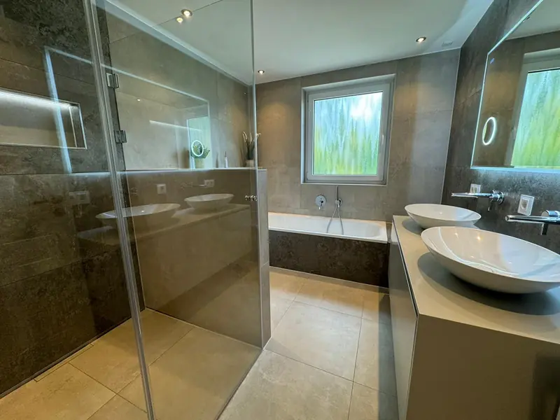 Badezimmer mit Glasdusche, Badewanne und Aufsatzwaschbecken