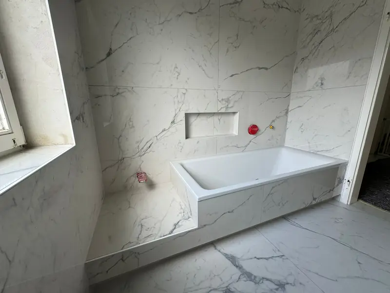 Badezimmer mit Marmoroptik-Fliesen und Badewanne kurz vor der Fertigstellung