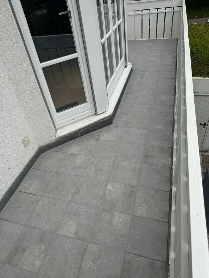 Balkon mit grauem Fliesenbelag und Geländer