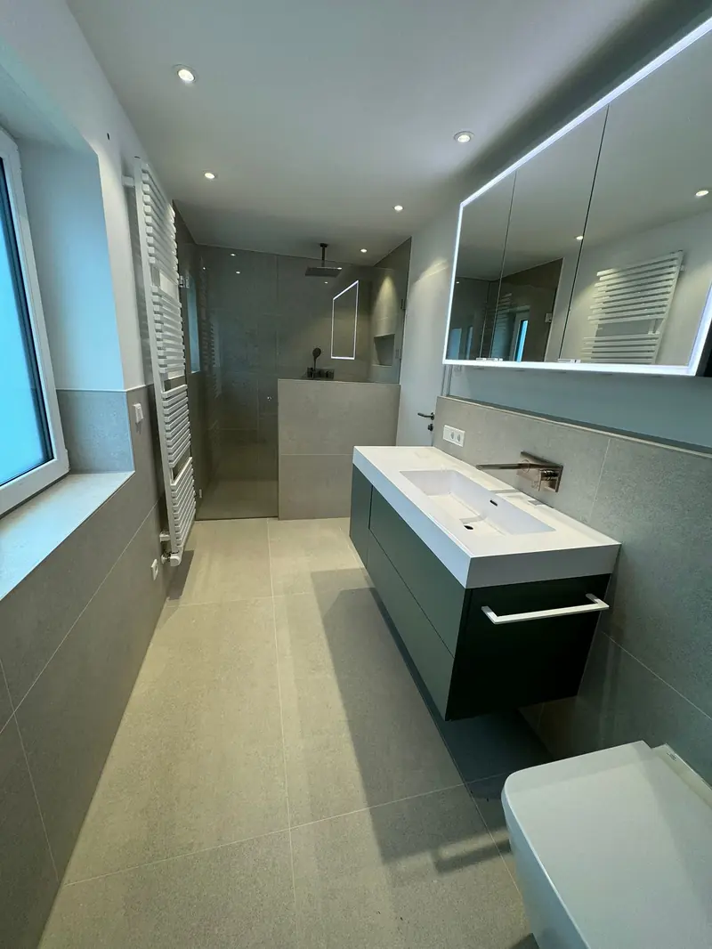 Schmales Badezimmer mit bodenebener Dusche, Waschtisch und Fenster