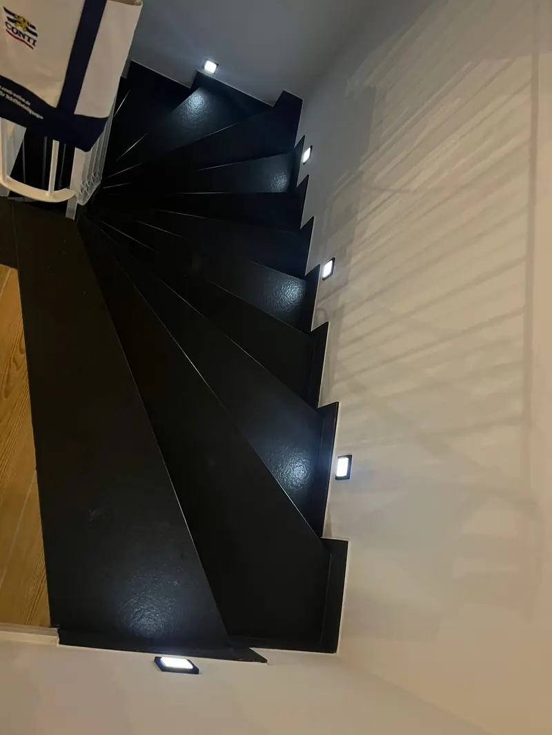 Schwarze Natursteintreppe mit Stufenbeleuchtung von oben