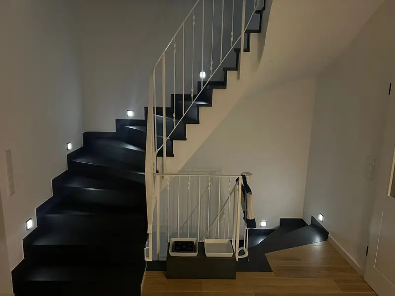 Schwarze Natursteintreppe mit Stufenbeleuchtung im Einfamilienhaus