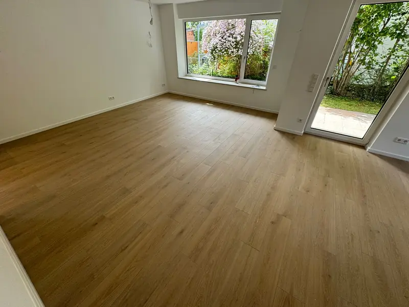 Wohnraum mit neu verlegtem Bodenbelag in Holzoptik und Gartenzugang